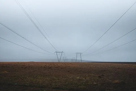 Power lines stretch endlessly across the misty Icelandic plains, disappearing Photos
