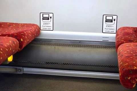Power Outlets on Train with Red Patterned Seats and Underseat Charging Options Stock Photos