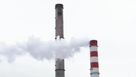 Power plants release clouds of smoke against a gray sky in an urban landscape Vídeos de archivo 295346445