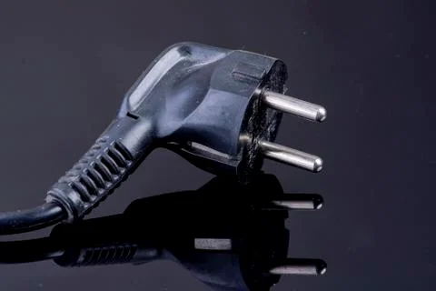 Power plug on reflective black surface Stock Photos