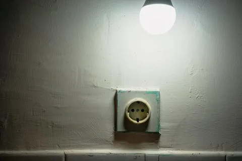 Power plug in the wall below the light bulb Stock-Fotos