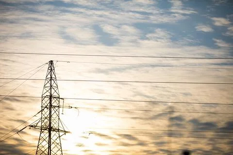 Power pole against the gently setting sun. High voltage power lines. 写真素材