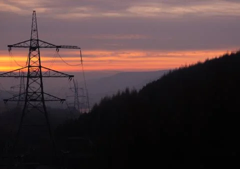 Power Pylons run through a forest at Sunset in the UK, Peak District Stock Photos