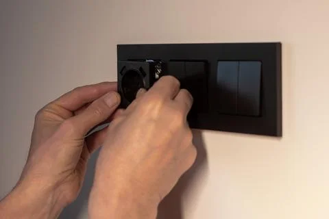 Power socket outlet installation in wall box in residential apartment. Hand.. Fotos de archivo
