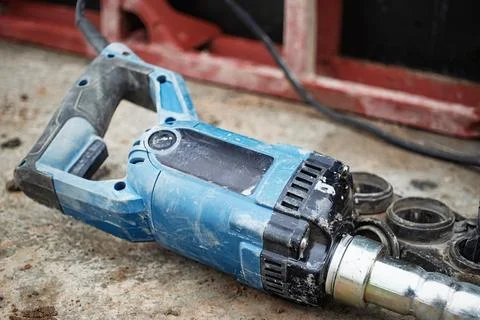 A power tool rests on a rugged surface at a construction site, showcasing dir Photos