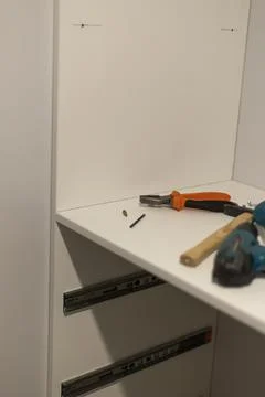 Power tools and hardware on white shelf in home office Stock Photos