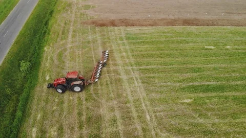 Power tractor red with working plow on the support wheels produces a tilling of Stock Footage 115826274