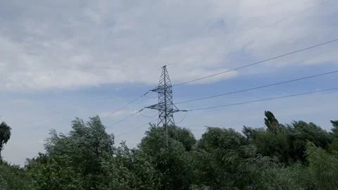 A power transmission tower stands in a forest against a blue sky Stock Footage 306167953