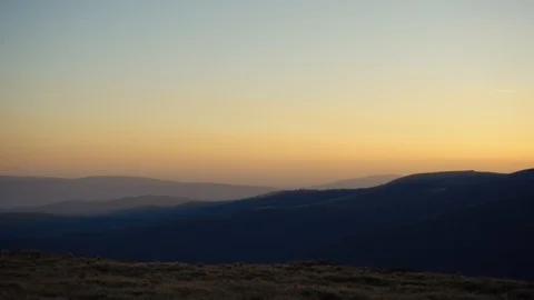 Power windmills in the mountains at sunset. Camera panning under a sunset light  Stock Footage 98377808