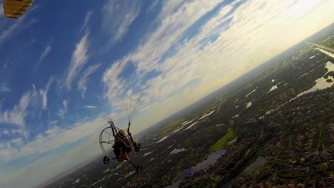 Powered paraglider pilot makes a big turn into the setting sun over a Video stock 116904870