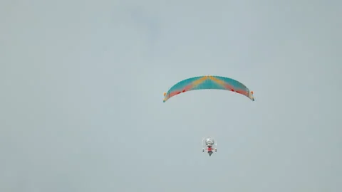 Powered paraglider pilot operates motorized trike paramotor with vibrant, 库存影片 318201478