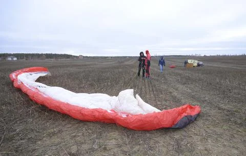 Powered paragliding. Men preparing the paramotor wing for flight in a field. Foto stock