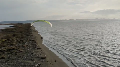 Powered paragliding paramotor flying over Albanian coast mountains and beaches Stockbeeldmateriaal 317488017
