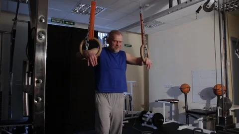 Powerful athlete at the age of push-ups and L sit on gymnastic rings Stock Footage 115252334