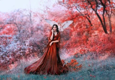 Powerful autumn nymph, queen of fire and goddess of hot sun, lady in long red Stock Photos
