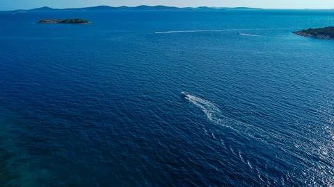Powerful boat tracing a path of white foam across the vast, deep blue sea Stock Photos