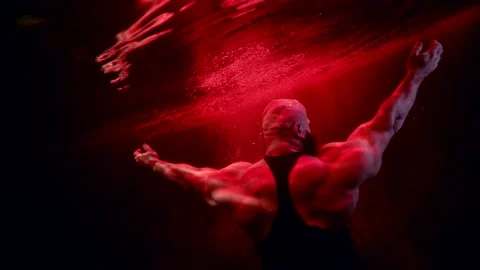 Powerful bodybuilder is floating in water of pool, showing his muscles, rear Видео 171066068