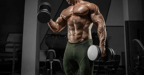 Powerful bodybuilder works out in a gym with dumbbells. No name portrait. B.. Foto stock