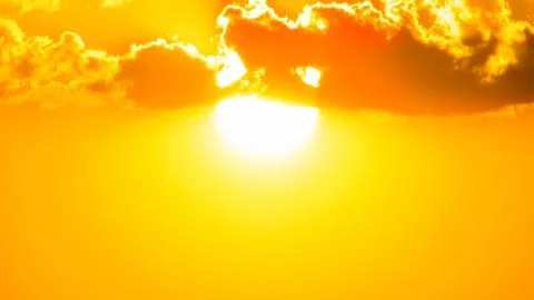 Powerful bright sun shining through vibrant orange and yellow clouds. A dra.. Stock Photos