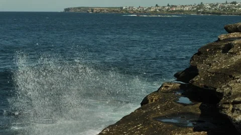Powerful crahing wave hits cliff with Coogee in distance slow motion 4K Stock Footage 274046576