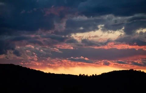 Powerful dramatic storm clouds illuminated by vibrant pink sunset light. Stock Photos