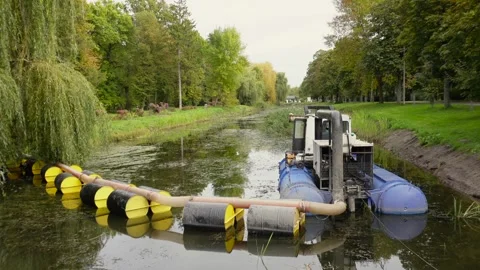 A powerful dredging machine works in a narrow canal, clearing sediment and .. Stock Footage 321918322