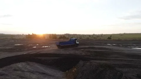 A powerful dump truck is driving off-road in the rays of the setting sun. A Stock Footage 169588748