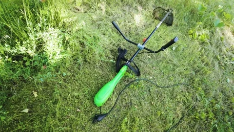 Powerful electric grass trimmer resting on grass after lawn mowing first pe.. Stock-Footage 340143623