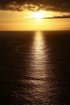 Powerful evening sunlight pierces dark clouds, creating a brilliant golden re Stockfoto's