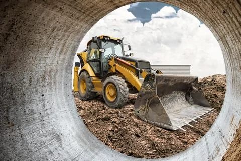 A powerful excavator-loader moves earth and debris at a construction site, .. 库存照片