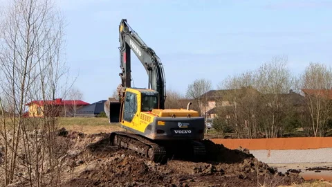 A powerful excavator VOLVO compares the ground in the park Stock Footage 182438987
