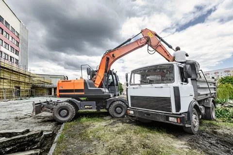 A powerful excavator is working at a construction site in the city, lifting a Stock Photos