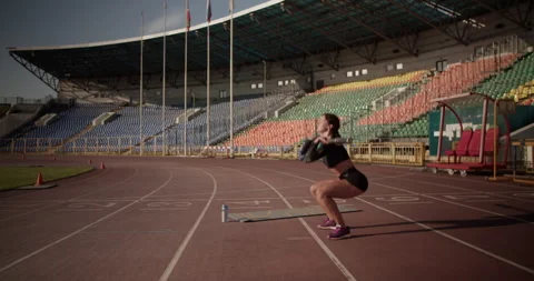Powerful female sprinter doing exercise with barbell at stadium Stock Footage 243627330