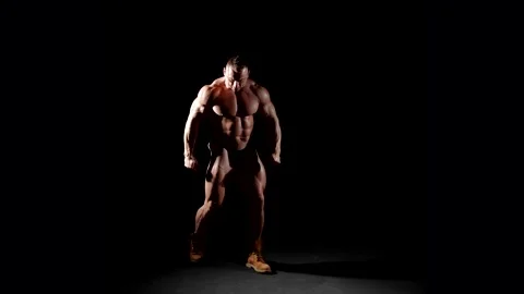 The powerful figure of a bodybuilder on a black background. His confident moveme 動画素材 297612549