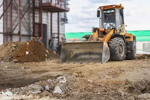 A powerful front loader on the construction site performs sanding. Stock Photos