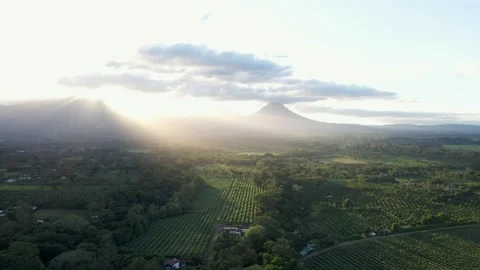 Powerful golden rays beaming onto green farming land with mountain peaks Stock Footage 169023981