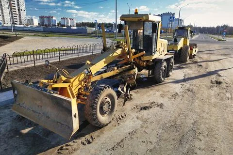A powerful grader plans the surface of the earth while building a new road. v 스톡 사진