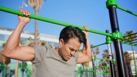 Powerful handsome guy doing pull ups at outdoor training spot at summer sunny Stock Footage 109419479