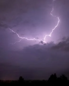 Powerful Lightning Bolt Cutting Through a Stormy Purple Sky at Night Stock Photos