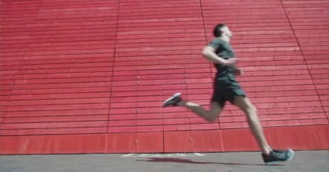 Powerful long limber runner jogging past wall. 스톡 동영상 58872725
