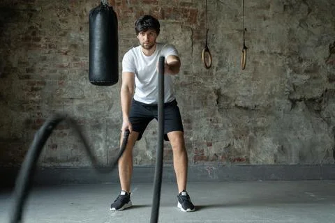 Powerful man training with rope in functional training fitness gym. Crossfit Stock Photos