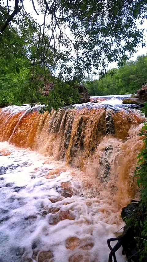 Powerful murky waterfall cascading over rocks Stock Footage 322674123