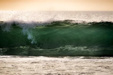 Powerful ocean wave crashes with emerald green water and sea spray 库存照片