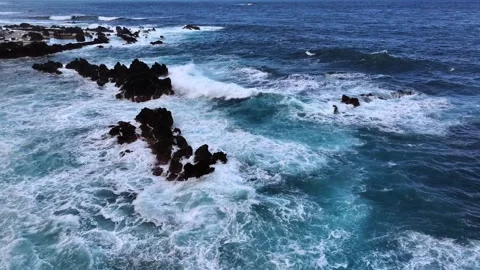 Powerful ocean waves crash against rugged black rocks Video stock 321944123
