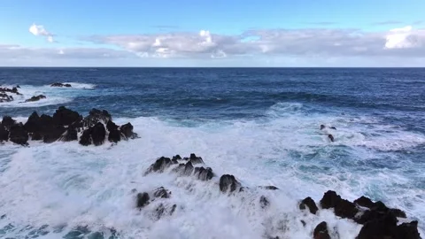 Powerful ocean waves crash against rugged black rocks Video stock 321944124