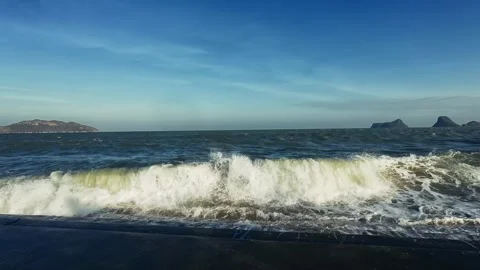 Powerful ocean waves crash against dark concrete shore with distant islands Stock Footage 326716391