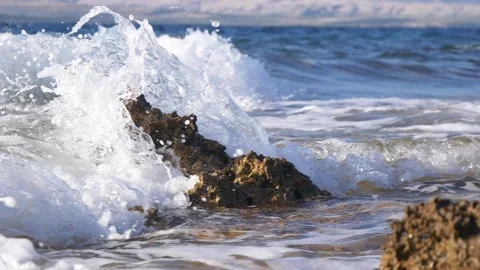 Powerful ocean waves crash against dark rocks with white foam Stock Footage 337414710