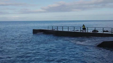 Powerful ocean waves crash against a sturdy concrete pier, sending sprays of Stock Footage 346889867