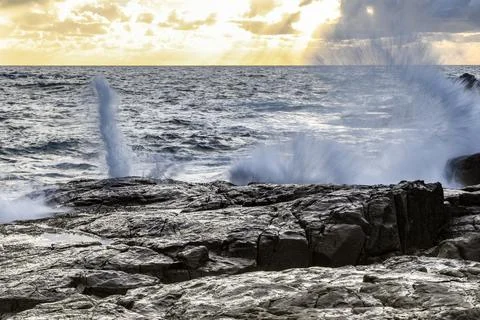 Powerful ocean waves crash dramatically against a rugged rocky coastline Stock Photos