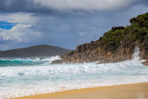 Powerful ocean waves crash dramatically against a rugged rocky coastline Stock Photos